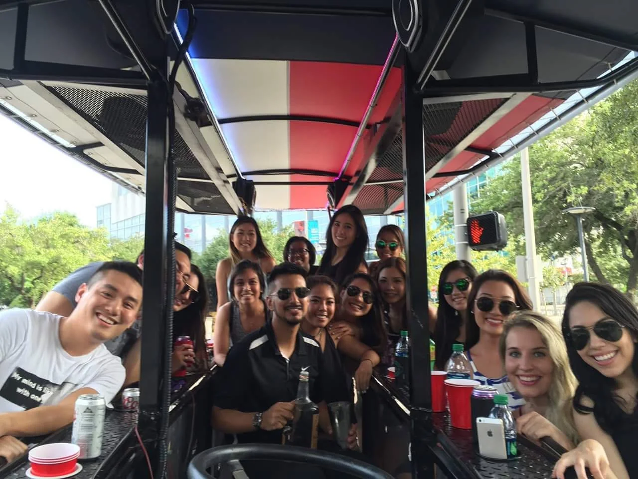A group crowded around the bar counter on the Houston Bike Bar under its red and white canopy