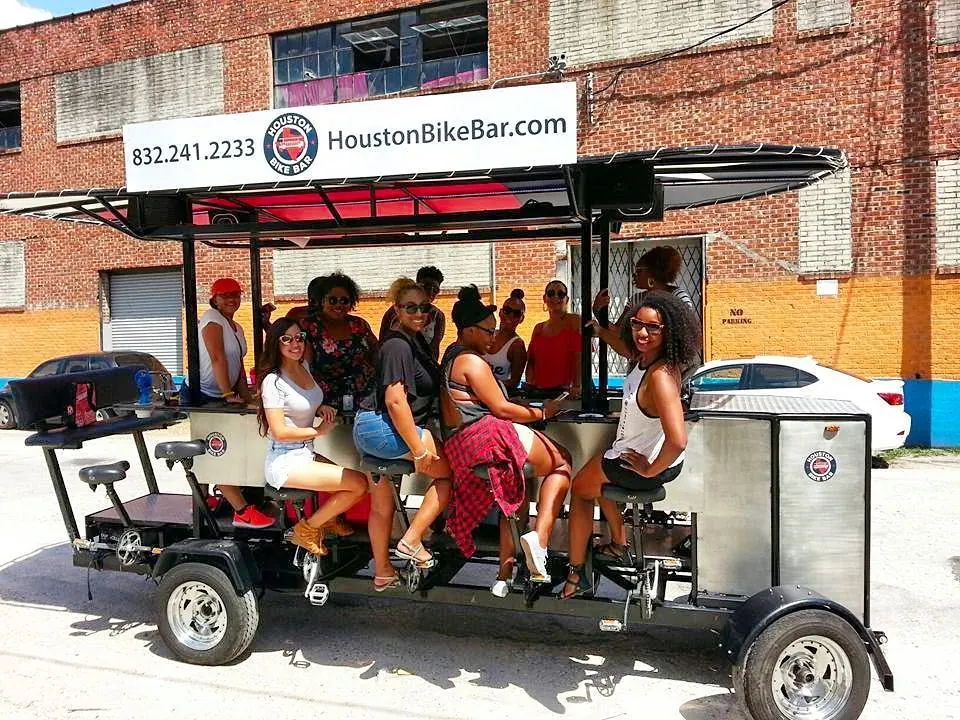 A group of friends seated around the bar of the Houston Bike Bar on a sunny afternoon in Midtown