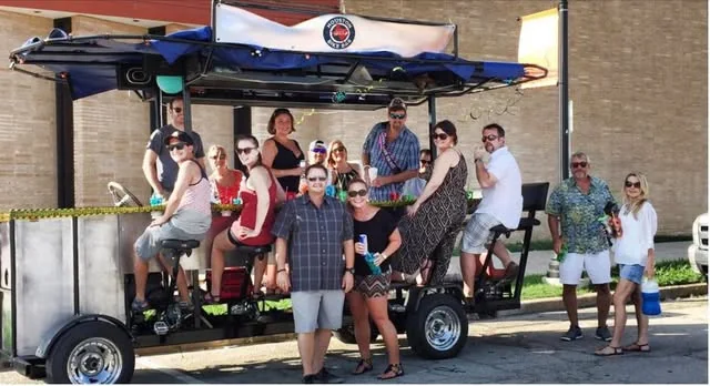 A group posing on and beside the Houston Bike Bar on a sunny afternoon