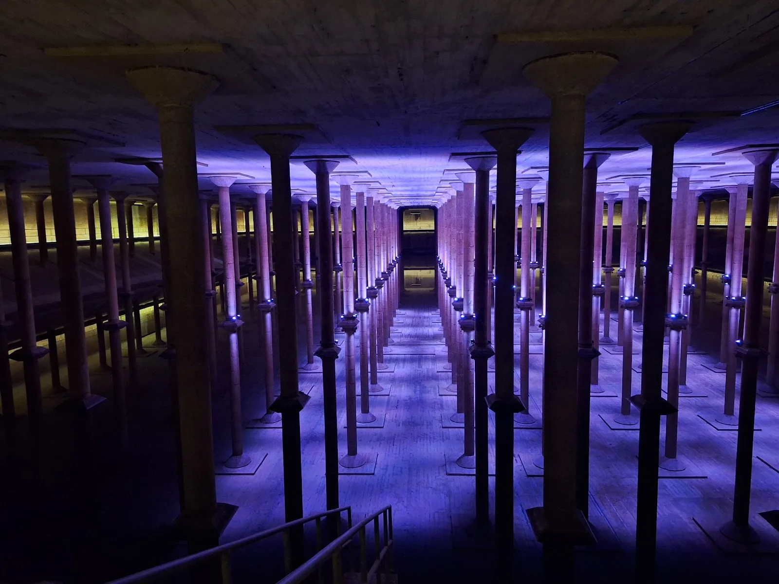 Purple-lit columns reflected in water inside the Buffalo Bayou Park Cistern
