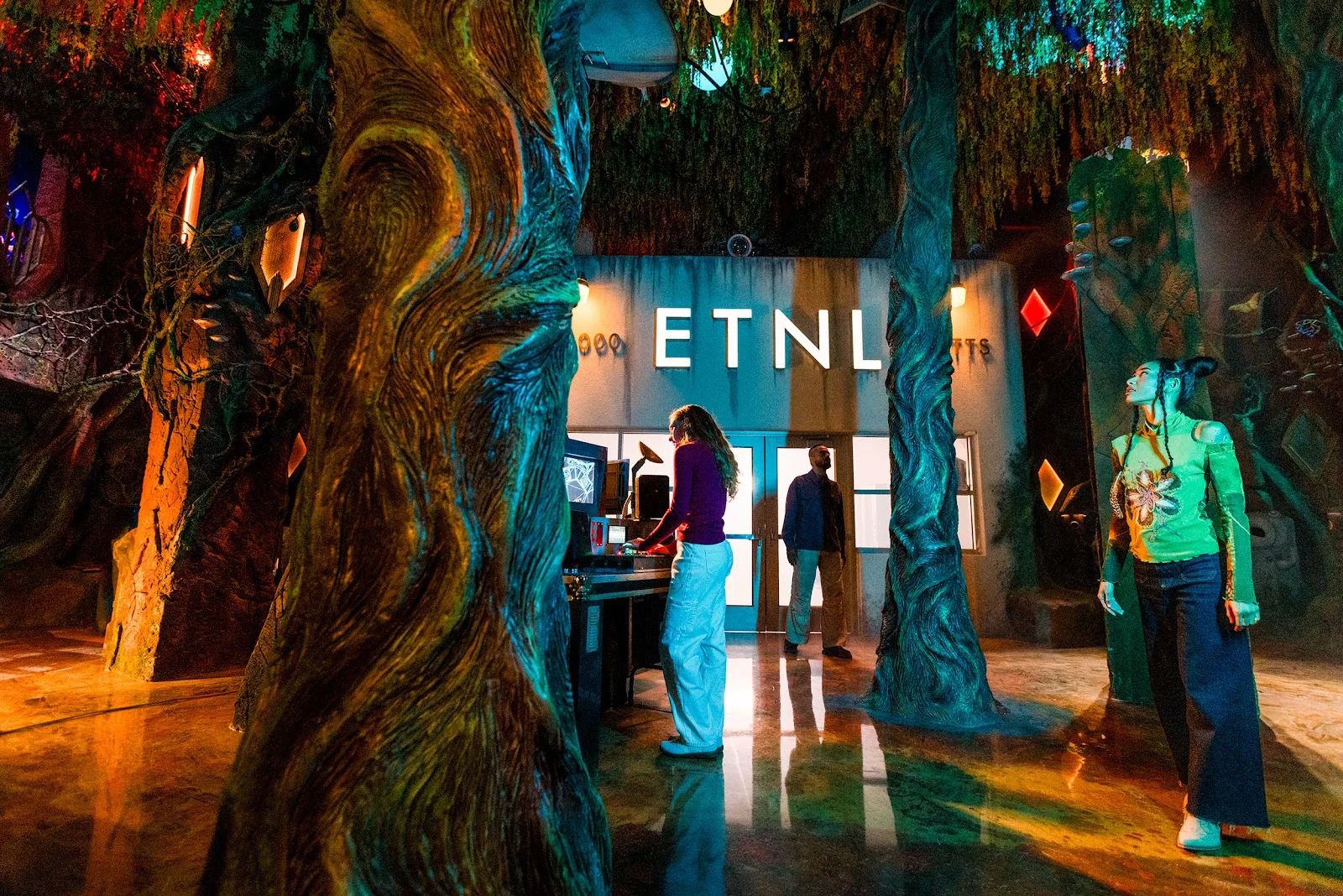 Visitors among twisted glowing trees in front of the ETNL radio station inside Meow Wolf&rsquo;s Radio Tave in Houston