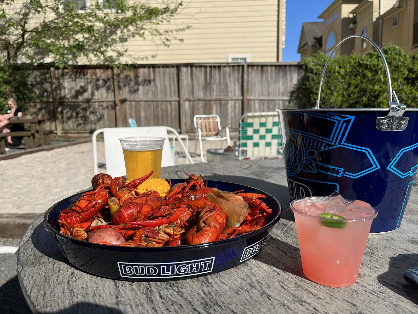 A tray of boiled crawfish, a beer and a frozen drink on a picnic table on the East End Hardware patio