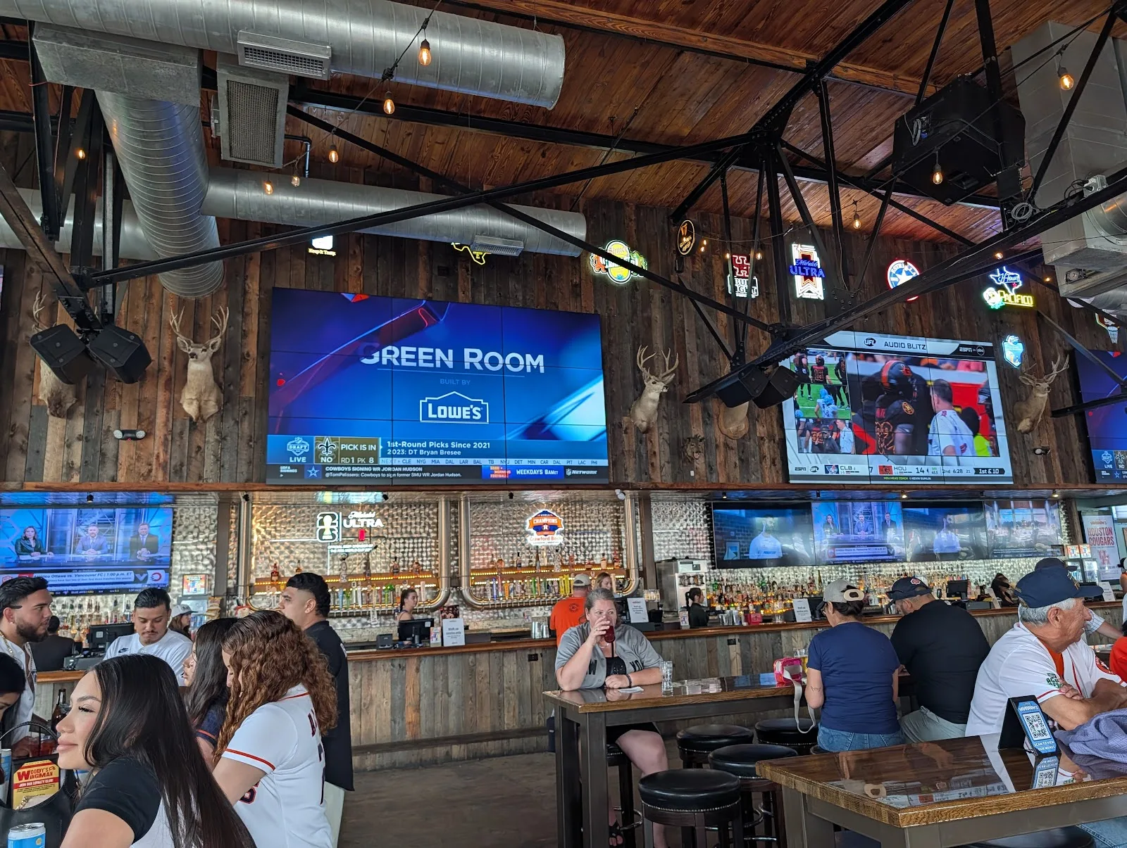 The bar and wall of screens inside Little Woodrow&rsquo;s EaDo on a game day, with fans in Astros jerseys