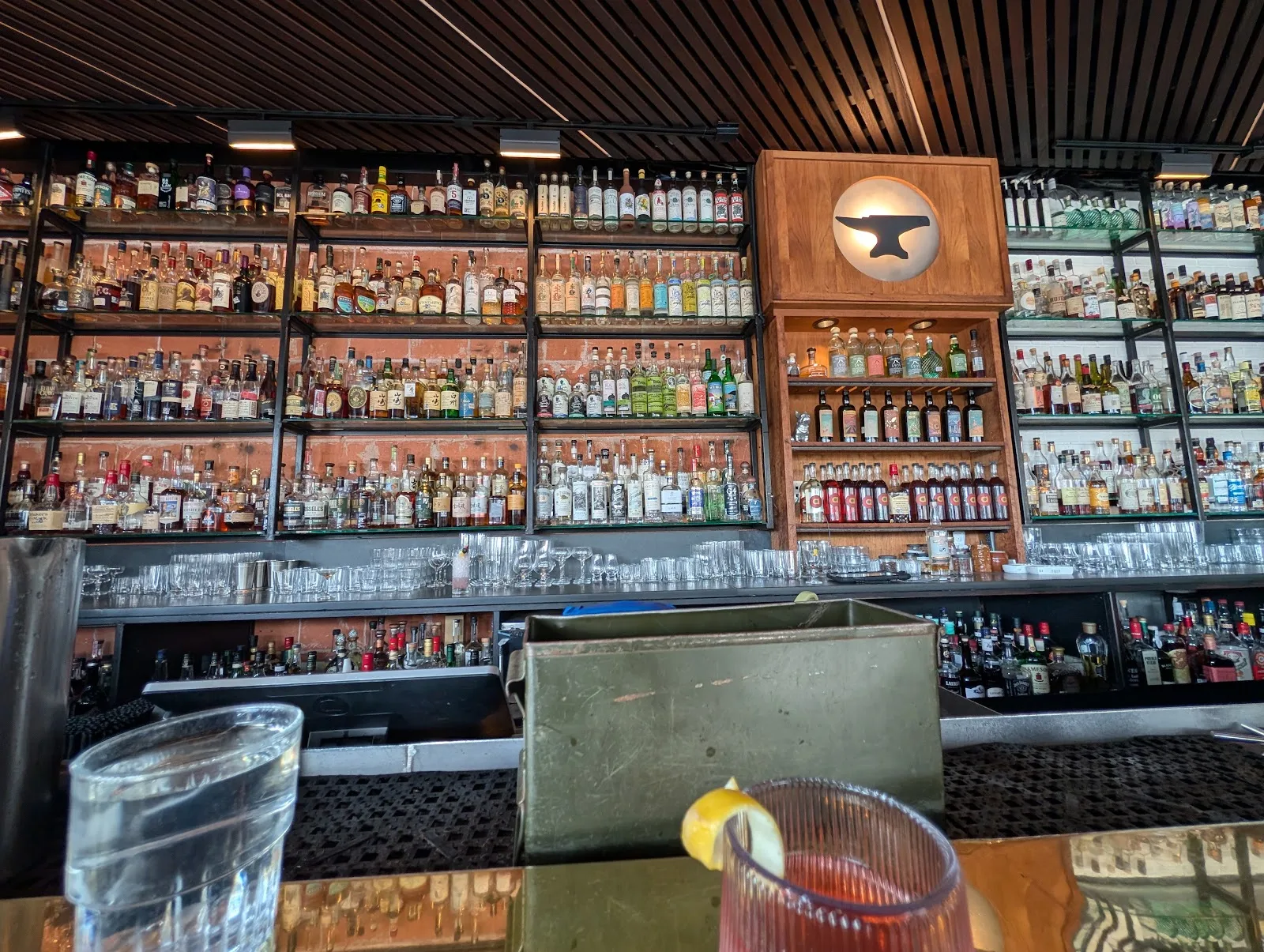 The back bar at Anvil on Westheimer, shelves of bottles under the anvil logo