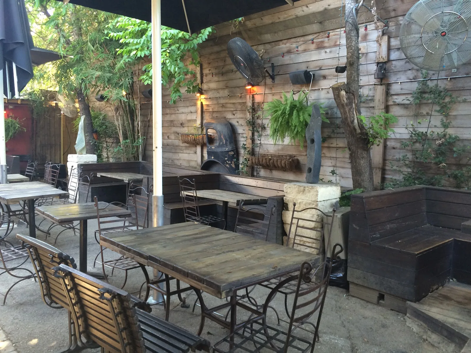 Wooden tables, iron chairs and ferns on the shaded patio at Boheme on Fairview