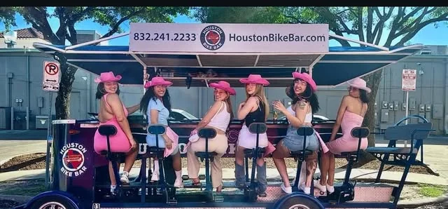 A bachelorette group in pink cowgirl hats on the bike bar