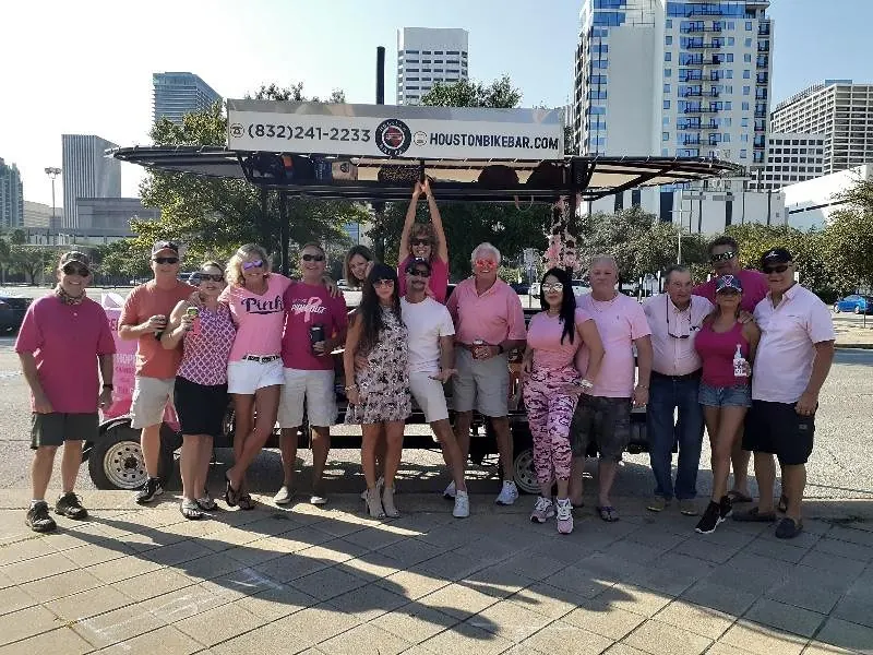 A group in pink hats riding the Houston Bike Bar during the day